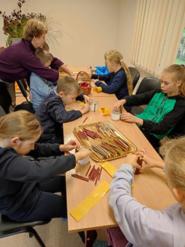 Kūrybinės dirbtuvės „Dovana mokytojui“. Jaunos merginos gamina dovanas mokytojoms. Moliūgai. Gėlės. Šakelės. Spalvotas popierius.