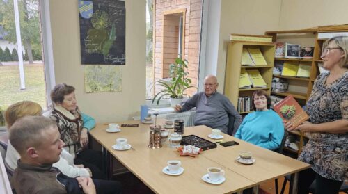 Bibliotekininkė 5 senjorams pasakoja apie knygą „Laimingas senelių gyvenimas“. Senjorais geria kavą, arbatą. Vaišinasi saldainiais.