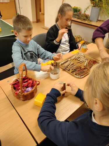 Kūrybinės dirbtuvės „Dovana mokytojui“. Jaunos merginos gamina dovanas mokytojoms. Moliūgai. Gėlės. Šakelės. Spalvotas popierius.