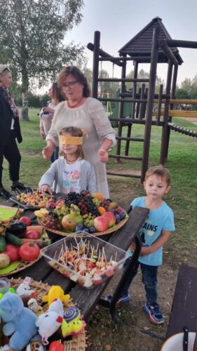 Užrištomis akimis bando atspėti vaisių ar daržovę. Vynuogės, obuoliai, mangas, bananas, slyvos, nektarinai, pomidorai, cukinija, paprikos, svogūnai, česnakai. Čiulpinukai. Muilo burbulai. Berniukas mėlyna palaidine. Vaikų žaidimų aikštelė