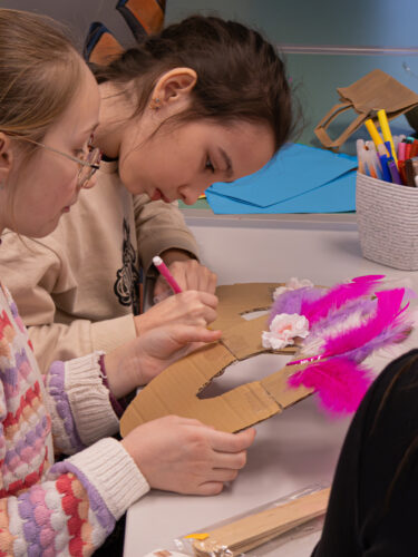 Vaikai Elektrėnų savivaldybės viešojoje bibliotekoje dalyvauja edukacinėje veikloje „Užgavėnių belaukiant". Gamina kaukes.